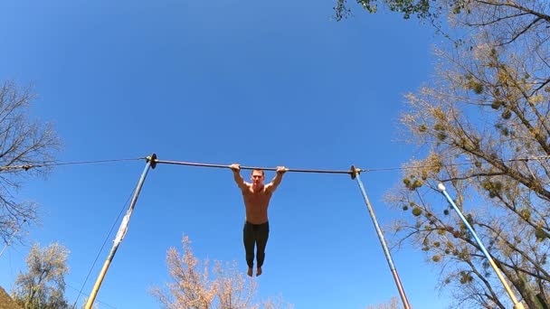 Gymnast does tricks on horizontal bar outdoor. Healthy lifestyle, calisthenic and workout concept — Stock Video