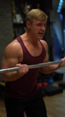 Spor salonunda egzersiz yapan kaslı vücut geliştiren adam. İrade, motivasyon ve tutku kavramı. 4k dikey çekim 