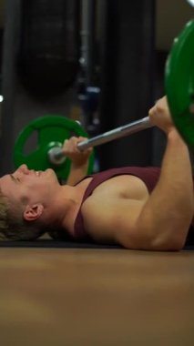 Spor salonunda egzersiz yapan kaslı vücut geliştiren adam. İrade, motivasyon ve tutku kavramı. 4k dikey çekim 