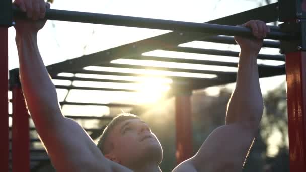 日没の空の背景でプルアップを行う筋肉の男。石灰岩,健康的なライフスタイルとワークアウトの概念 — ストック動画