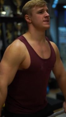 Spor salonunda egzersiz yapan kaslı vücut geliştiren adam. İrade, motivasyon ve tutku kavramı. 4k dikey çekim 