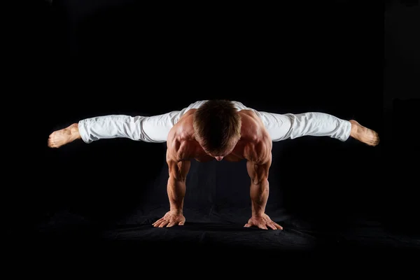 Artista de circo mantiene el equilibrio por un lado aislado sobre un fondo negro. Concepto de fuerza de voluntad, motivación y estilo de vida saludable —  Fotos de Stock