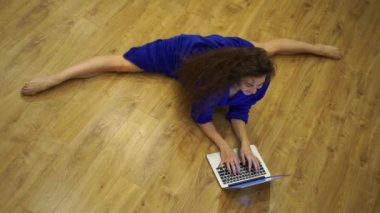 Çok esnek bir kadın dizüstü bilgisayarının önünde bacaklarını esnetiyor. Bireysellik, yaratıcılık ve kendine güven kavramı