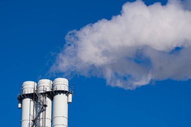 Mavi gökyüzüne karşı borulardan çıkan dumandan kaynaklanan hava kirliliği. Çevre kirliliği, çevre sorunları ve emisyonları kavramı