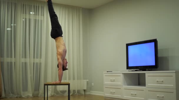 A muscular man doing handstand and watch TV. Concept of originality, creativity and outstanding — Stock Video