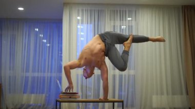 Kaslı bir adam bir elinde dengesini korur ve dizüstü bilgisayar kullanır. İrade, motivasyon ve tutku kavramı