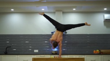 Adam bir elinde dengesini koruyor ve mutfakta yemek pişiriyor. Sağlıklı yaşam tarzı, yoga ve sağlık konsepti