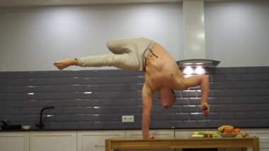 Adam amuda kalkıp mutfakta yemek pişiriyor. Yoga, sağlık ve sağlıklı yaşam tarzı kavramı 