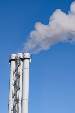 Mavi gökyüzüne karşı borulardan çıkan dumandan kaynaklanan hava kirliliği. Çevre kirliliği, çevre sorunları ve emisyonları kavramı