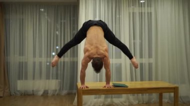 Kaslı bir adam bir elinde dengesini korur ve dizüstü bilgisayar kullanır. Kişisel izolasyon, tele çalışma ve uzak iş konsepti