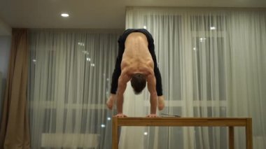 Kaslı bir adam bir elinde dengesini korur ve dizüstü bilgisayar kullanır. Özgünlük, yaratıcılık ve olağanüstü kavramı