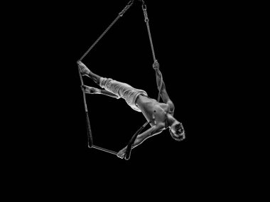 Kaslı erkek hava sirki sanatçısı dans trapeziyle performans sergiliyor.