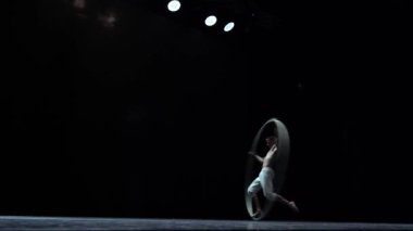 Muscular circus artist perform Cyr Wheel on a black background. Concept of willpower, motivation and passion.