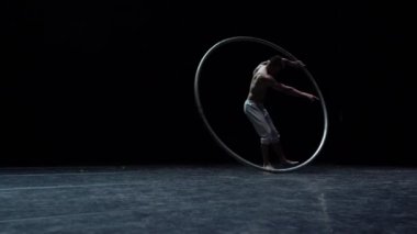 Kaslı sirk sanatçısı siyah arka planda Cyr Wheel performansı sergiliyor. Özgünlük, yaratıcılık ve olağanüstü kavramı.