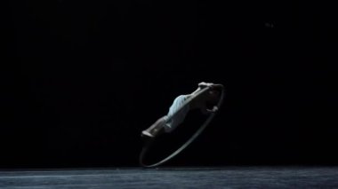Muscular circus artist perform Cyr Wheel on a black background.Concept of Individuality and creativity .