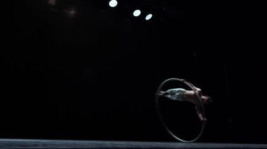 Muscular circus artist perform Cyr Wheel on a black background.Concept of Individuality and creativity .