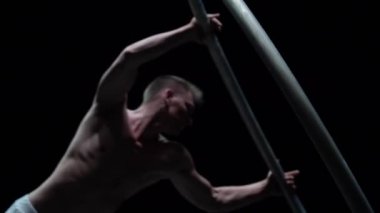 Muscular circus artist perform Cyr Wheel on a black background.Concept of Individuality and creativity .
