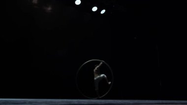 Muscular circus artist perform Cyr Wheel on a black background. Concept of originality, creativity and outstanding.