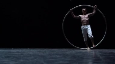 Kaslı sirk sanatçısı siyah arka planda Cyr Wheel performansı sergiliyor. Arzu, istek ve potansiyel kavramı.