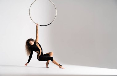 Flexible, fit female air circus artist performances with aerial hoop.