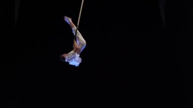 Kaslı erkek hava sirki sanatçısı dans trapeziyle performans sergiliyor.