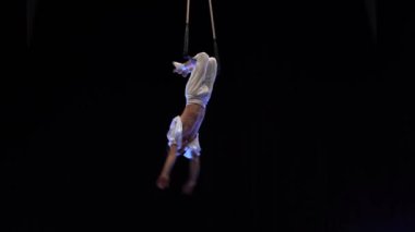 Kaslı erkek hava sirki sanatçısı dans trapeziyle performans sergiliyor.