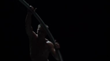 Kaslı sirk sanatçısı siyah arka planda Cyr Wheel performansı sergiliyor. Arzu, istek ve potansiyel kavramı.