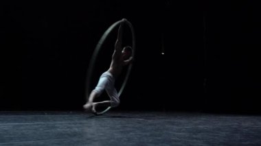 Muscular circus artist perform Cyr Wheel on a black background.Concept of Individuality and creativity .