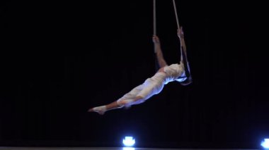 Kaslı erkek hava sirki sanatçısı dans trapeziyle performans sergiliyor.