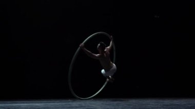 Kaslı sirk sanatçısı siyah arka planda Cyr Wheel performansı sergiliyor. Özgünlük, yaratıcılık ve olağanüstü kavramı.