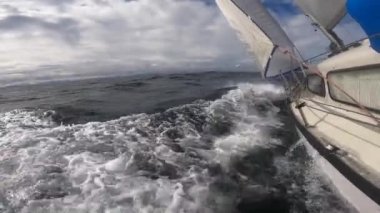 Sailboat Hull Cutting Through Water bending on the side through stormy weather, Bow Wave.