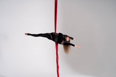Flexible circus Artist performs on the aerial silk on white background. Concept of willpower, motivation and passion.
