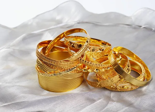 Frauen kostbare goldene Armbänder, auf grauer Seide — Stockfoto