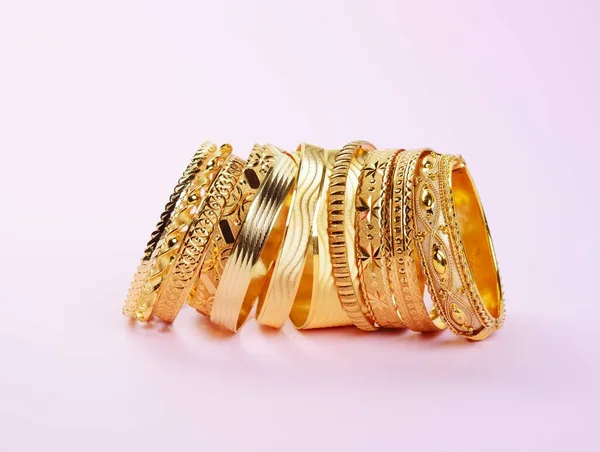 Womans precious golden bracelets, on a pink — Stock Photo, Image