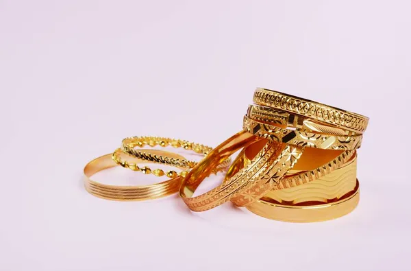Женщины драгоценные золотые браслеты, на розовом — стоковое фото