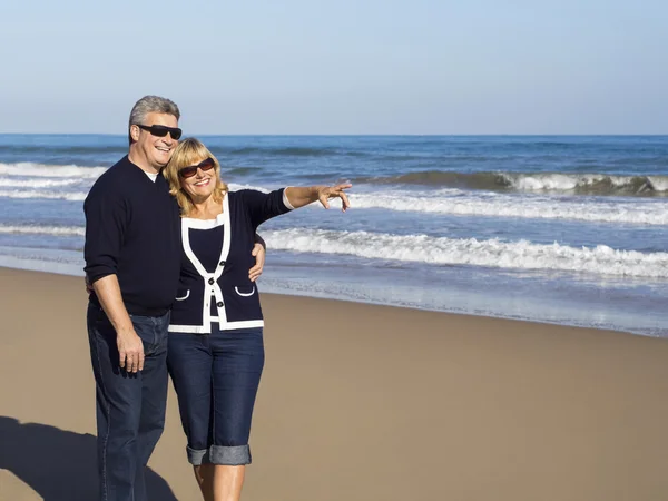 Feliz casal maduro aponta para em um dia ensolarado na praia — Fotografia de Stock