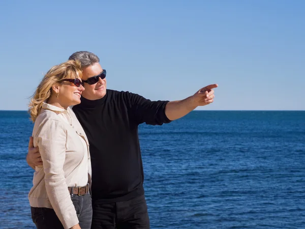 Affectueux couple d'âge mûr au bord de la mer pointant copyspace — Photo