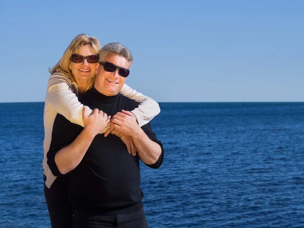 Feliz amoroso maduro casal posando contra um azul oceano — Fotografia de Stock