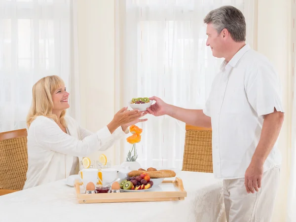 Mature senior husband serving his wife healthy breakfast — Stock Photo, Image