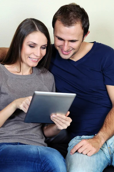 Casal usando um computador tablet em sua sala de estar — Fotografia de Stock