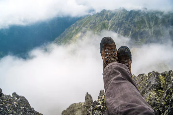徒步旅行者在云层在山高休息 免版税图库照片