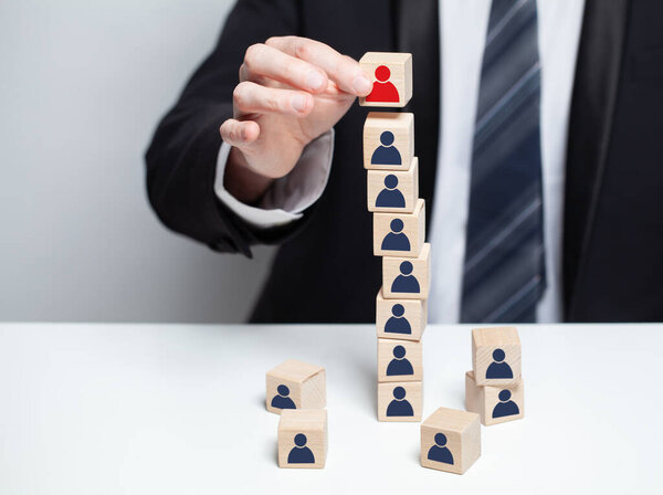 Businessman hand putting wooden cube block with red head symbols on top