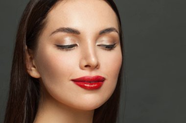Zarif makyajlı güzel bir kadın yüzü. Yakın çekim. Kırmızı dudaklar, altın göz farı ve siyah göz kalemi.
