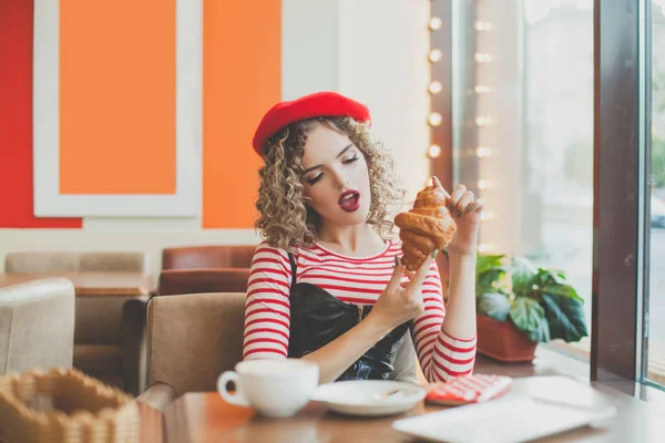 街のカフェでクロワッサンを食べる美しい若い女性 — ストック写真