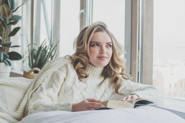 Evde kitap okuyan hoş bir genç bayan.