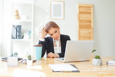 Modern ofiste çalışırken masa başında yorgun ve genç bir ofis çalışanı.