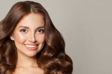 Kahverengi kıvırcık saçlı, gülümseyen güzel bir kadının moda stüdyo portresi. Moda ve güzellik