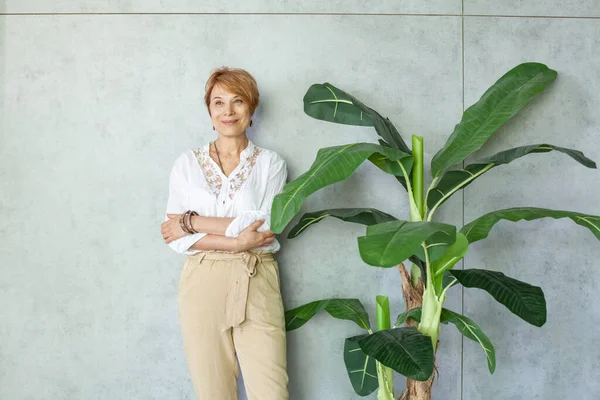 緑の葉植物と灰色の背景に健康な成熟した女性の肖像画 — ストック写真