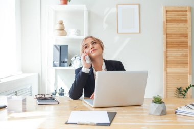 Modern ofiste cep telefonu kullanan genç bir iş kadını