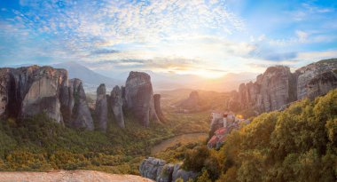 Yunanistan 'ın Meteora kentindeki kayaların ve manastırların muhteşem manzarası. Güneşli bir günde mavi gökyüzü ve beyaz bulutlarla güzel güneşli bir sabah.